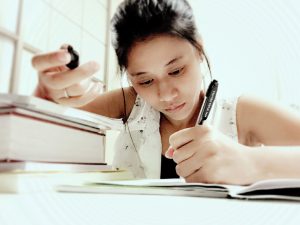 Teenage Girl Next to Books Writing