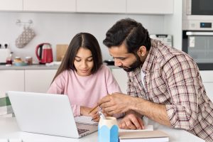 Father and daughter in kitchen with laptop
