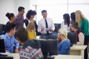 group of students with teacher in computer lab classrom learrning lessons, get help and support