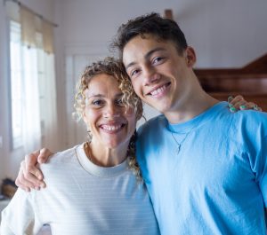 Portrait of grateful teenager man hug smiling middle-aged mother show love and care, thankful happy grown-up son in embrace cheerful mom, enjoy weekend family time at home together, bonding concept